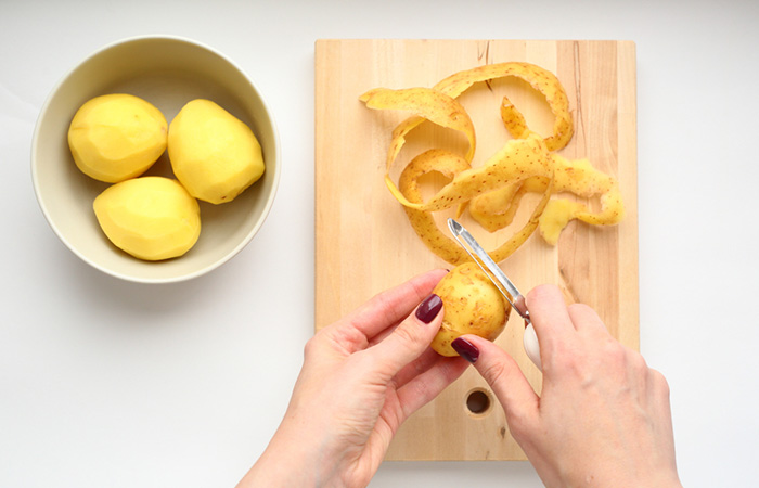Woman peeling potatoes to make potato juice