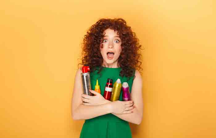 Woman holding many haircare products that may cause product buildup and dandruff 