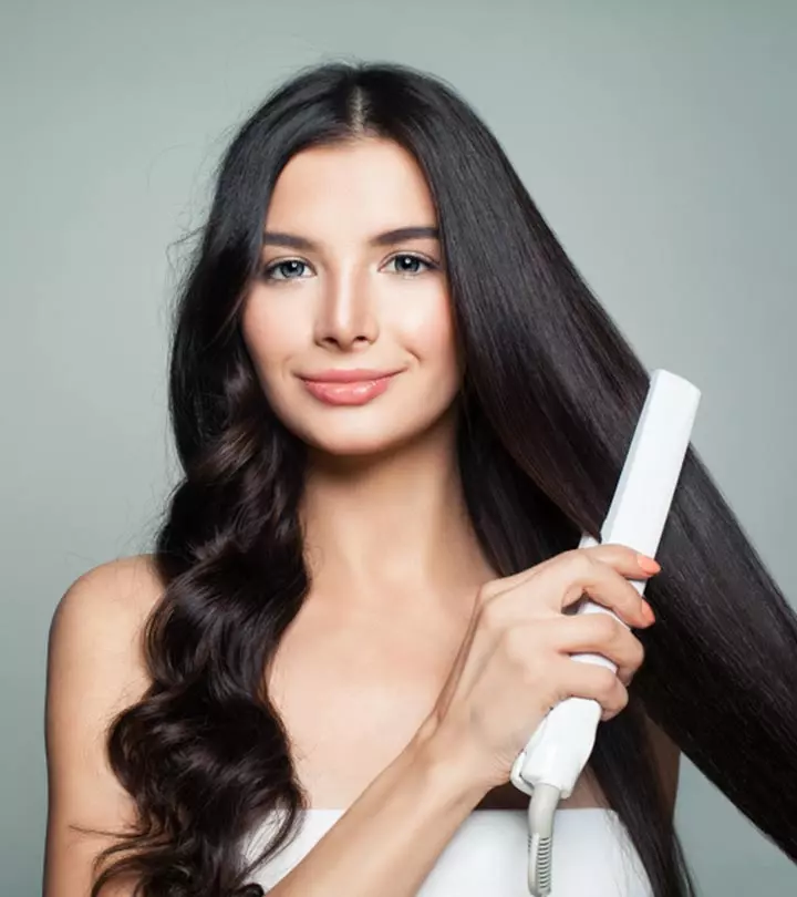 women with damp hair using hair straightener