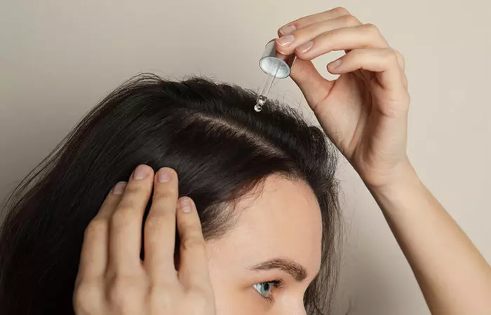 Woman applying minoxidil to her scalp