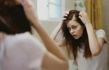 Woman with alopecia looking at mirror