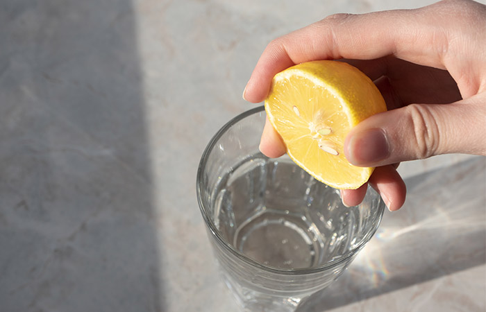 Hand squeezing lemon juice in a glass of water