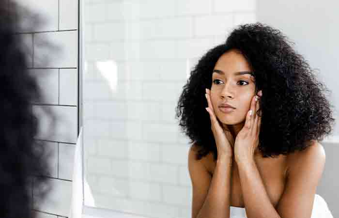 Woman looking at mirror trying to determine her skin type