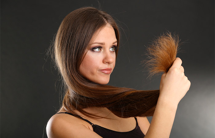 Woman diagnosing hair damage by checking split ends