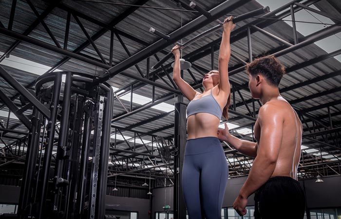 Trainer helping a woman do hanging exercise to increase height