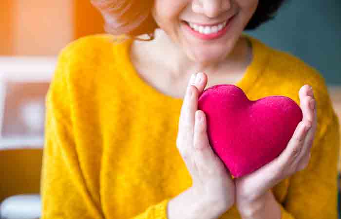 Smiling woman holding pink heart