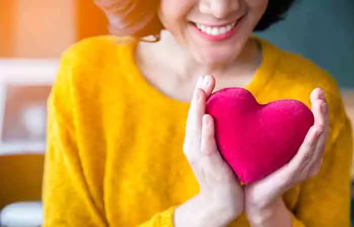 Smiling woman holding pink heart
