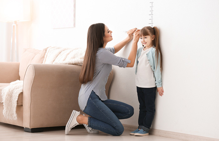 Woman measuring her daughter’s height