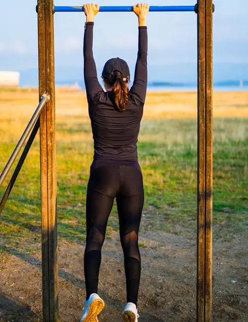 A woman doing the bar hang pull-up exercise