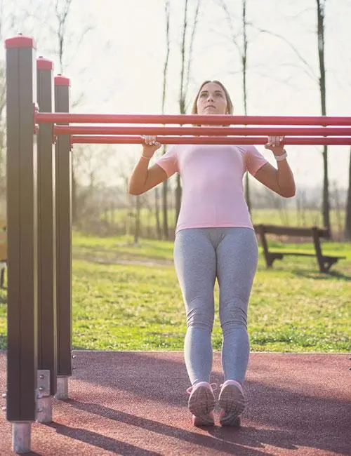 A woman doing the flexed arm hang pull-up exercise