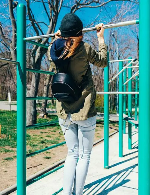 A woman doing hanging reverse shoulder shrugs