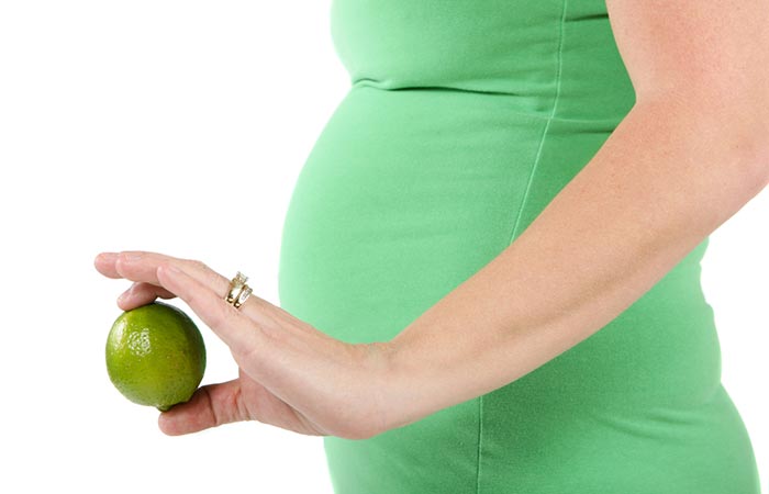 Side view of tummy of pregnant woman as she holds a lime in one hand