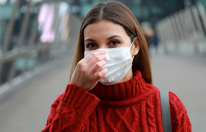 Woman covering nose and mouth while outside to avoid runny nose