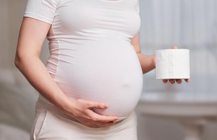 Pregnant woman holding a tissue roll indicating good bowel movement