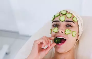 Woman applying cucumber on her sensitive skin