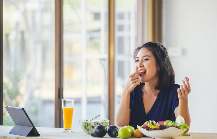 A happy woman enjoying a variety of fresh fruits and veggies.