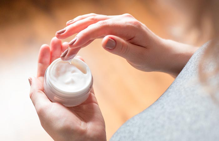 Woman applying moisturizer to look young