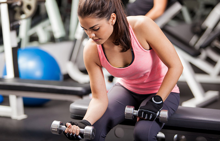 Woman doing dumbbell curls to prevent tennis elbow