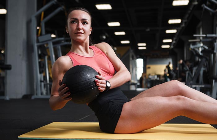 Woman doing seated Russian twist with weights