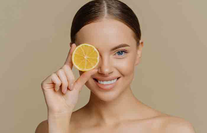 Woman holding a slice of lemon over her eye