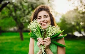 Healthy and happy woman holding a bouquet of lily of the valley