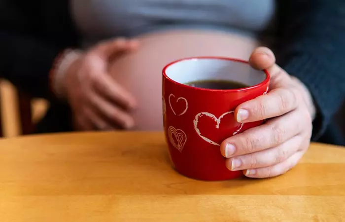 Pregnant woman holding cranberry tea cup