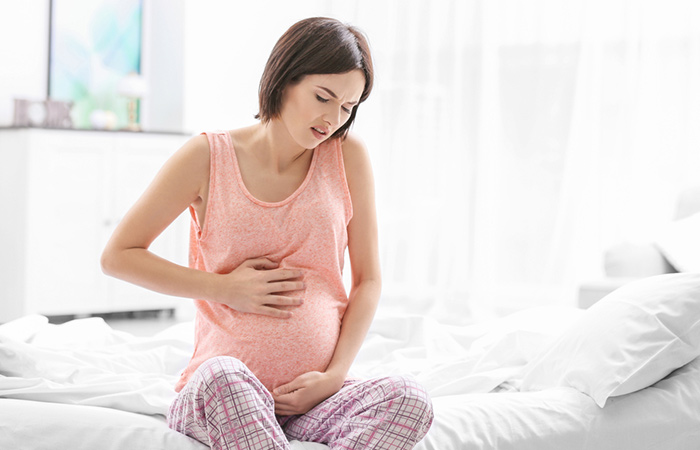 Young pregnant woman experiencing abdominal pain as a side effect of cucumbers