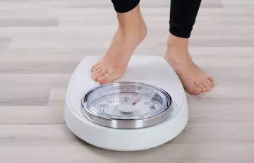 Woman about to step onto the weighing machine