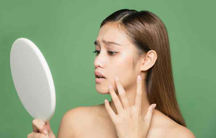 Woman examining her skin closely to see signs of breakouts 