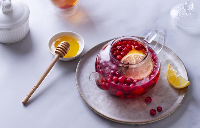 Glass teapot filled with cranberries and sliced lemons