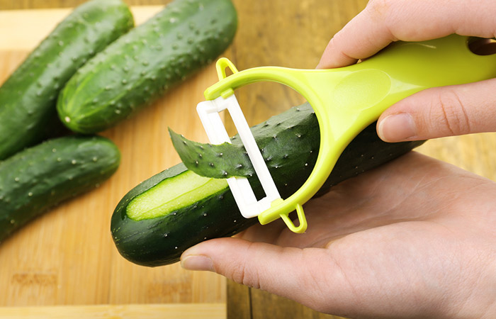 Close up of hands peeling cucumber
