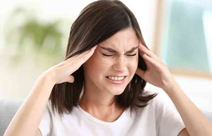 Woman touching her head due to headache as a side effect of peppermint tea