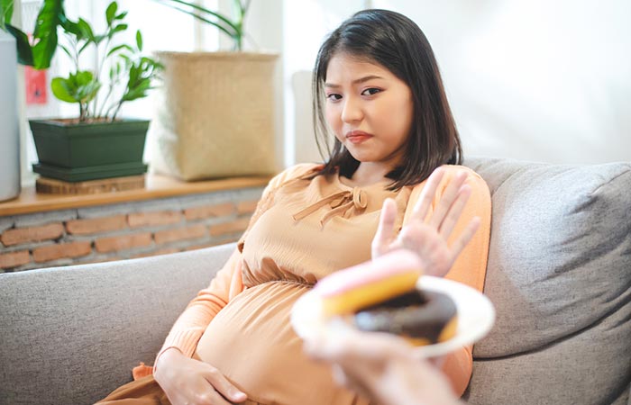 Pregnant woman saying no to donuts as a precaution to prevent sesame allergy