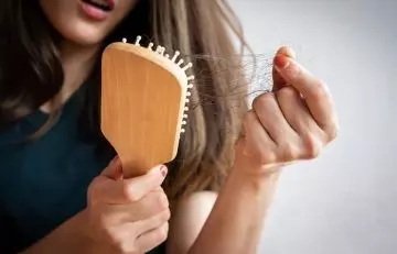 Woman looking at broken hair on brush