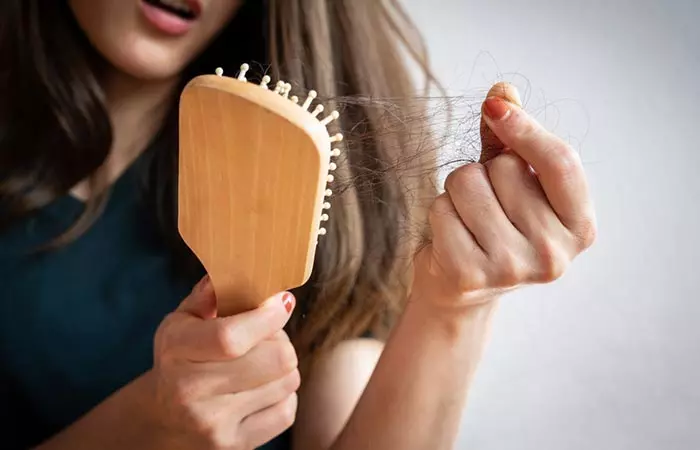Woman looking at broken hair on brush
