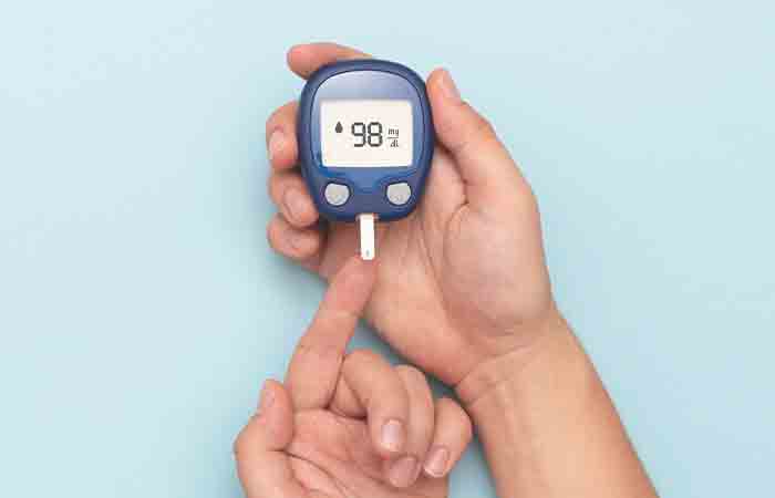 Woman using a glucometer as fenugreek tea benefits her by lowering her blood sugar level