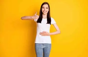 Woman happily touching her stomach as fenugreek tea benefits her by aiding digestion