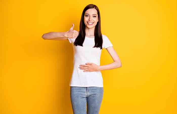 Woman happily touching her stomach as fenugreek tea benefits her by aiding digestion