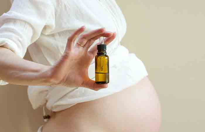 Беременная женщина держит бутылку эфирного масла