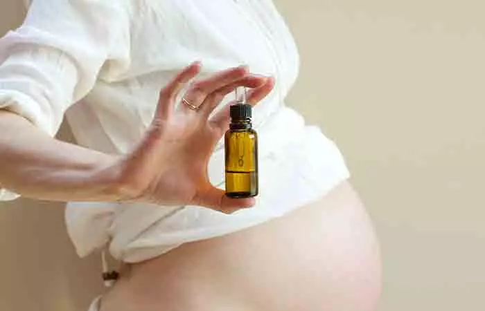A pregnant woman holding a bottle of essential oil