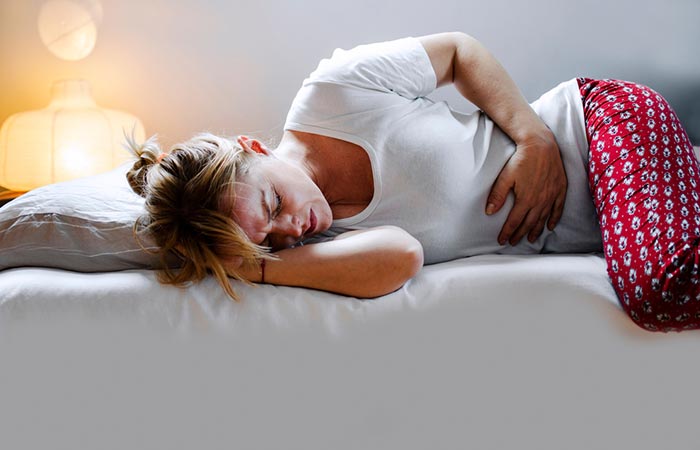 Woman with upset stomach lying on bed