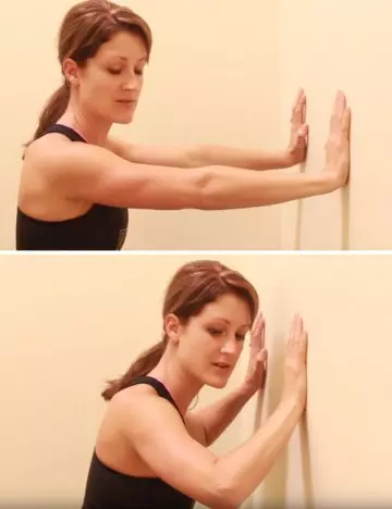 Woman doing wall push-ups for arm exercises without weights
