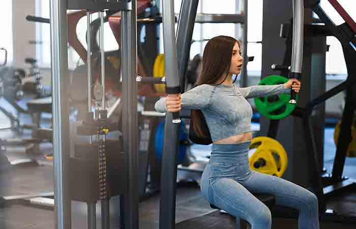 Woman performing butterfly chest workout with a cable machine