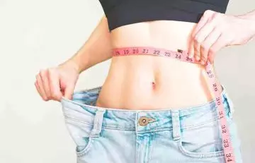Woman measuring her slim waist as a result of butterfly chest workout 