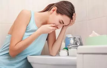 Woman vomiting near sink in the bathroom due to side effects of avocados