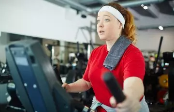 Woman working out on an elliptical machine to reduce weight