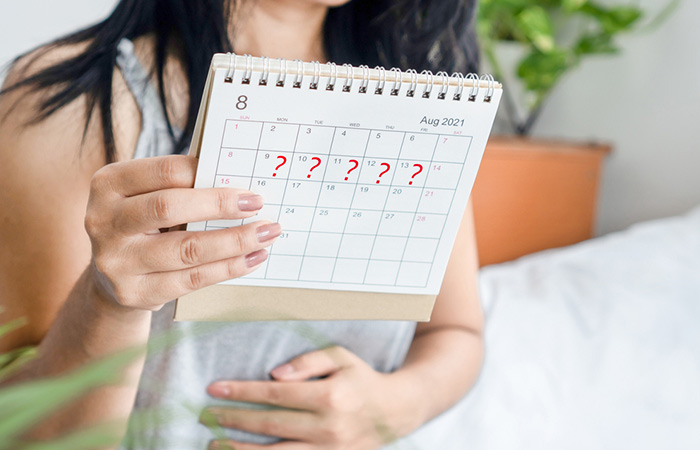 Woman noting her disturbed menstrual cycle on a calendar