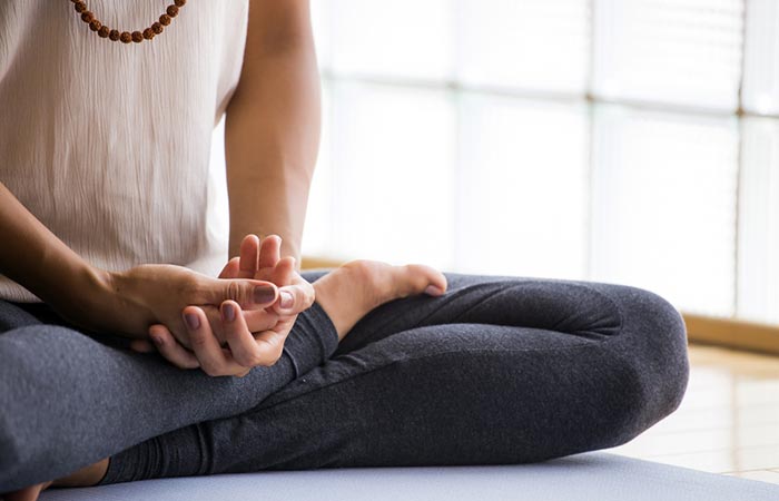 Woman sitting on yoga mat and meditating