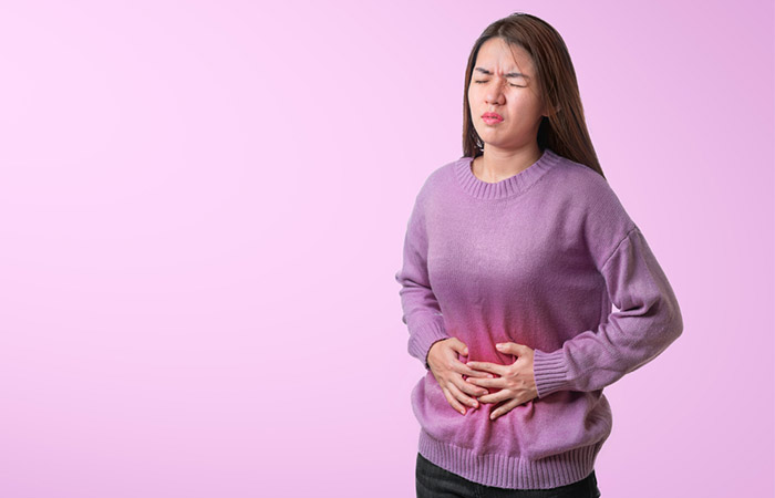 A woman experiencing stomach ache due to consuming excessive dates