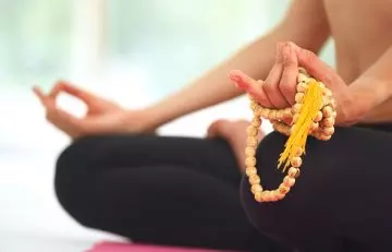 Woman sitting in lotus pose with beads used in mantra meditations